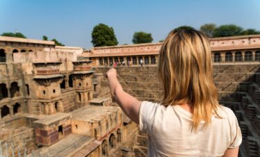 A Girl Traveler Pointing To Famous Stepwell Chand Baori.